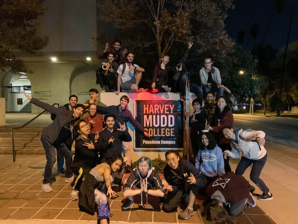 A group of Mudd students in front of a sign that says "Harvey Mudd College Pasadena Campus"