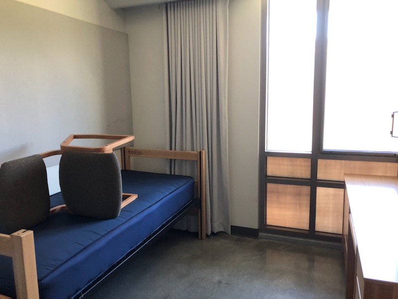 Dorm room with a chair on an empty bed facing an empty desk