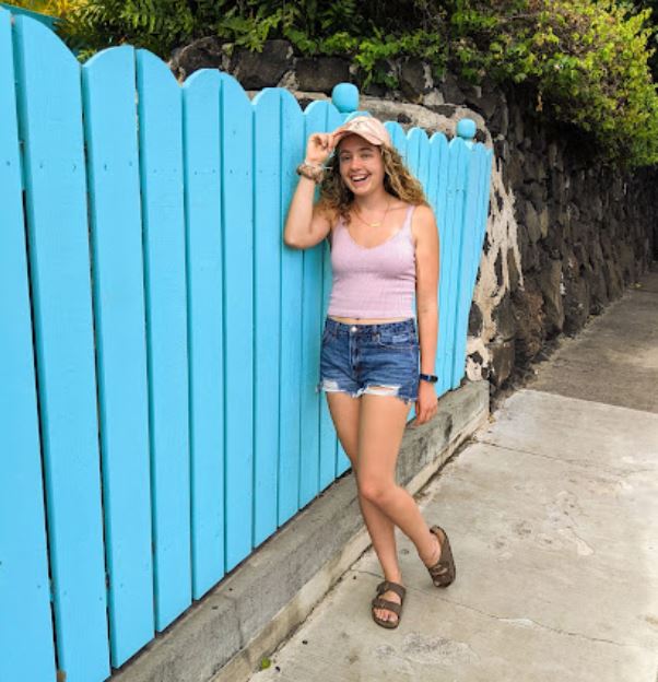 Mikayla in front of a blue fence