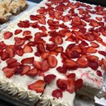 A large cake frosted white with strawberries on top