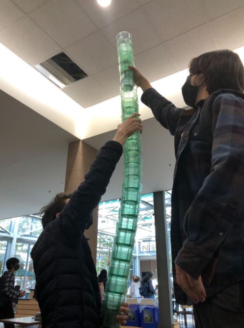 Two students stack a very large number of cups together
