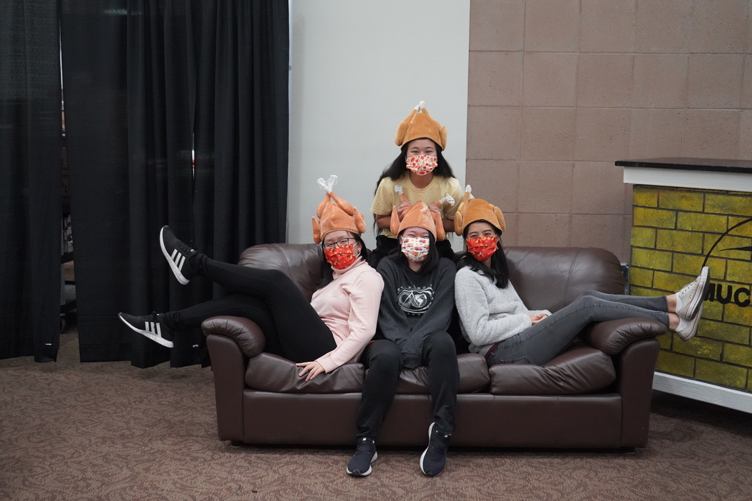 Four students on a couch with turkey hats on.