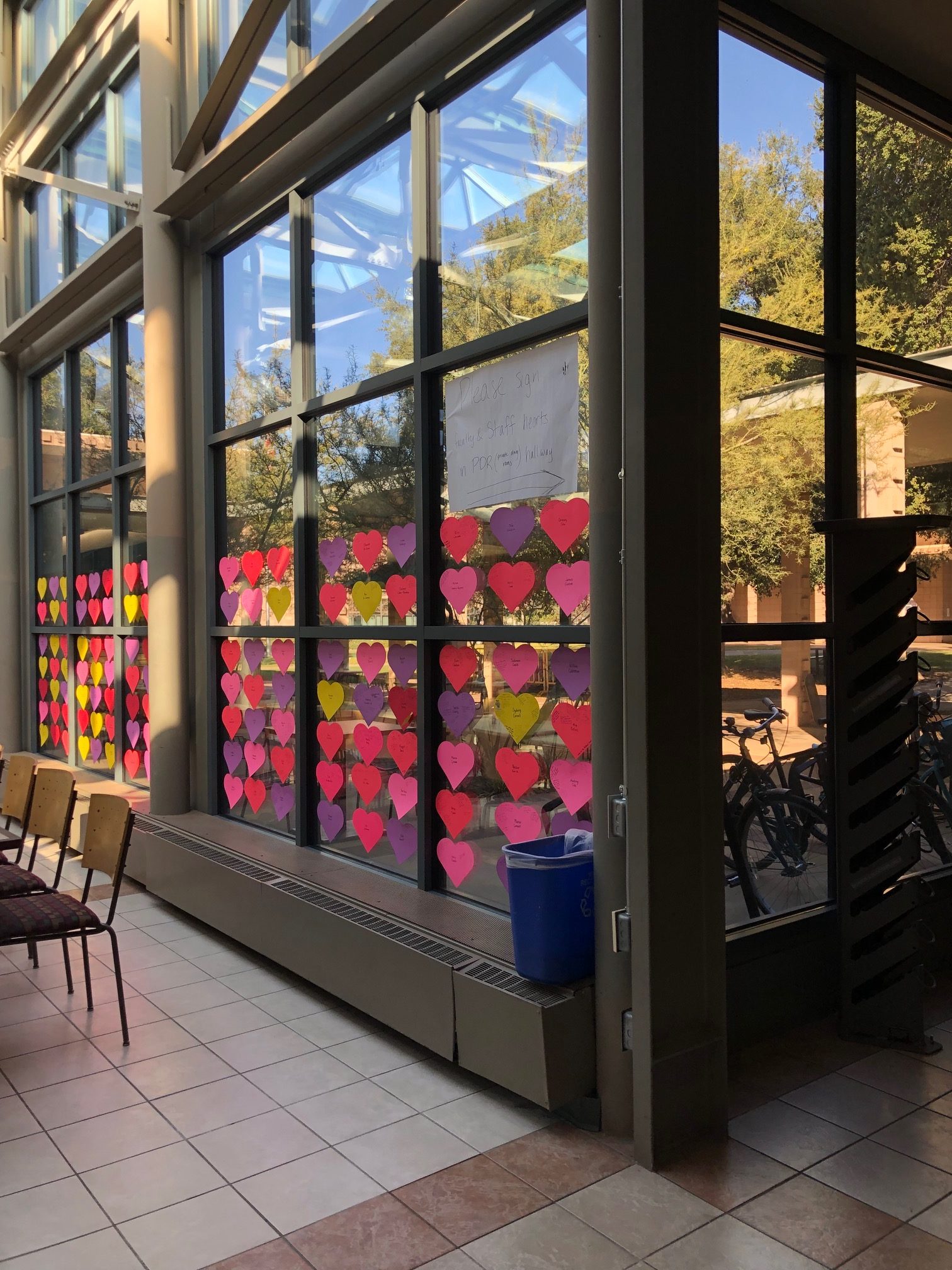 A wall of windows, with pink, purple, red, and yellow cut-out hearts on it