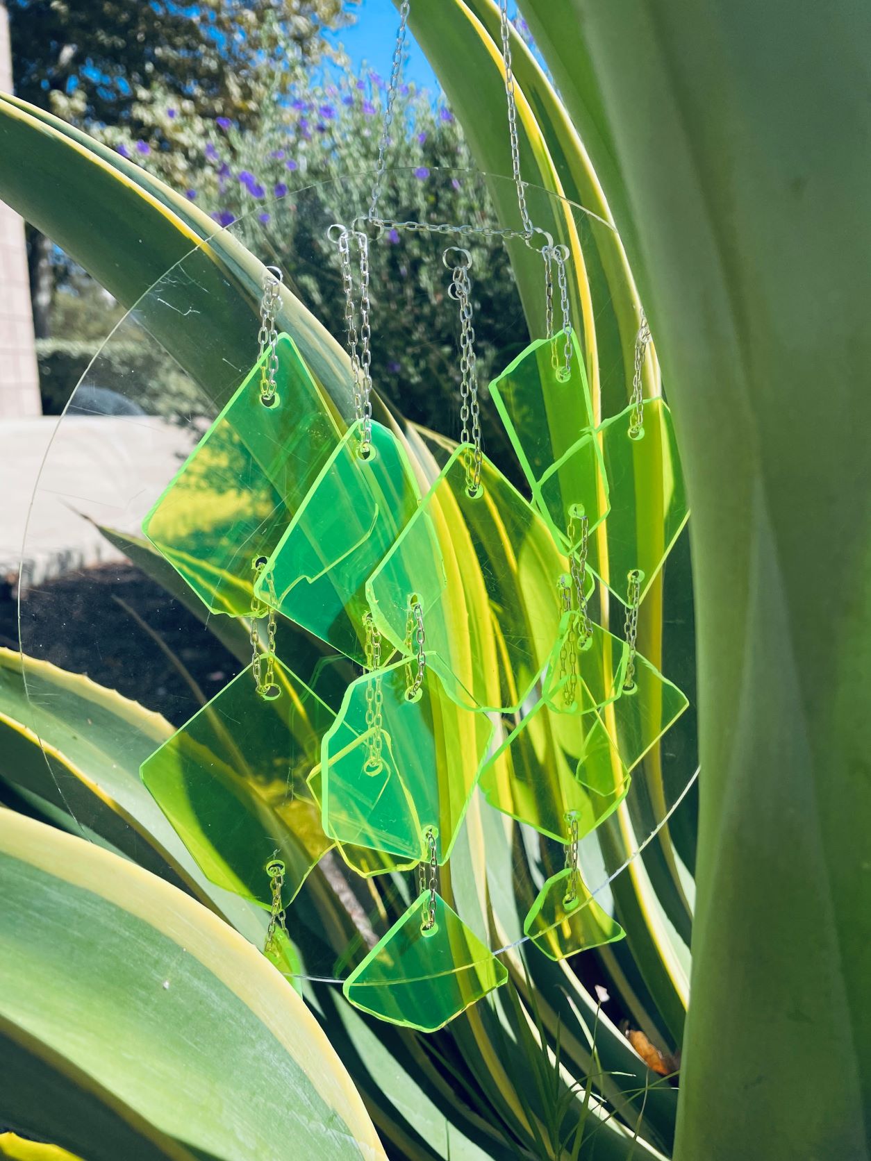 A green sun catcher hanging in a plant