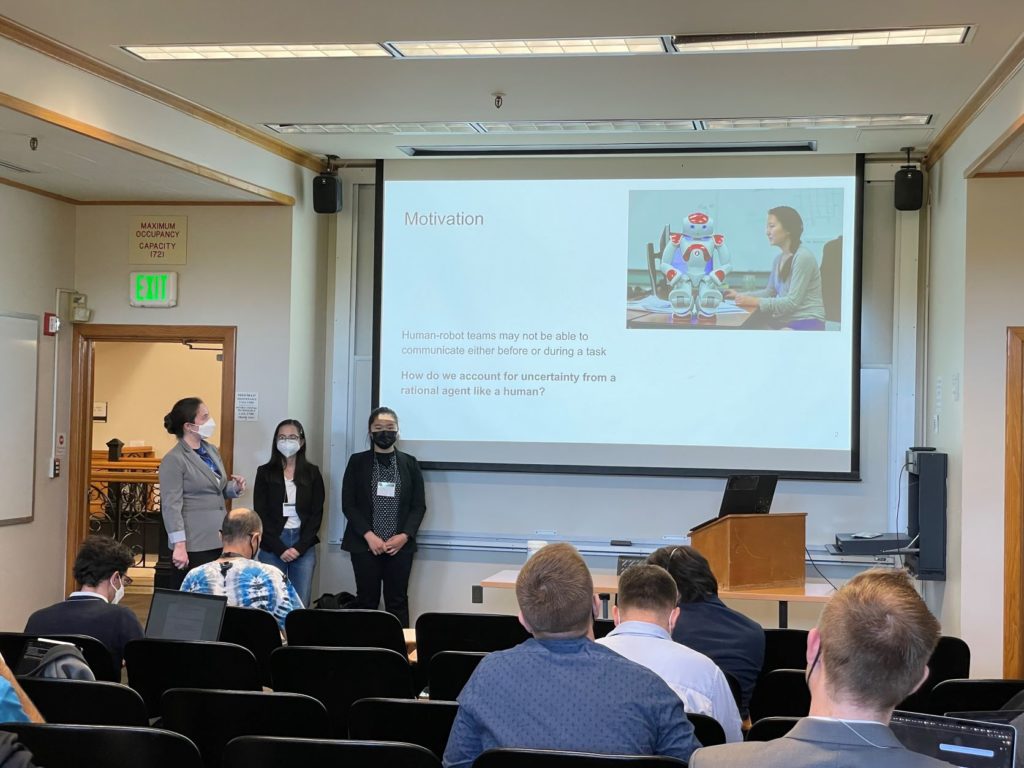 Three students in front of a screen--the screen reads "motivation" and has a photo of a student with a robot