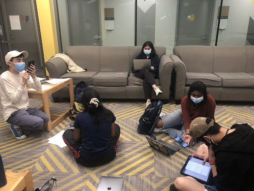 Friends sitting on couch and floor while working.