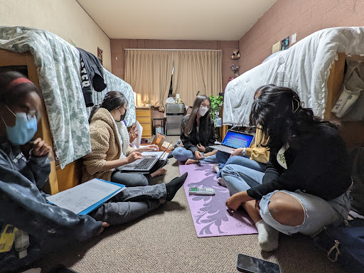 Students sit cross legged in dorm room