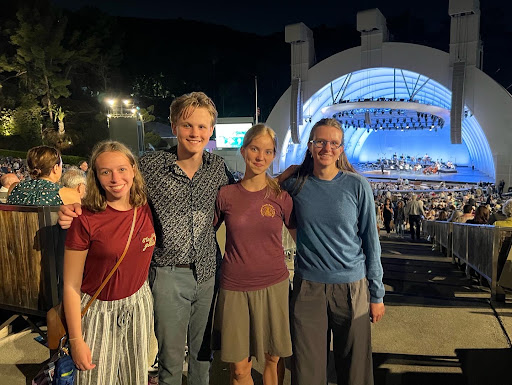 Four Mudd Students, smiling, standing in the audience of a venue with the Hollywood Bowl stage behind them.