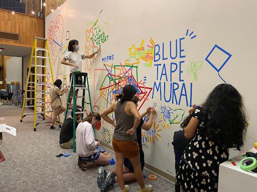 Colorful tape on the wall spells out "Blue tape mural"