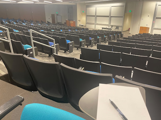 A pen and paper on a side table in a large empty lecture hall