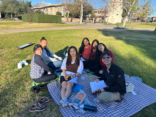 Group of students sitting together on a picnic blanket. 