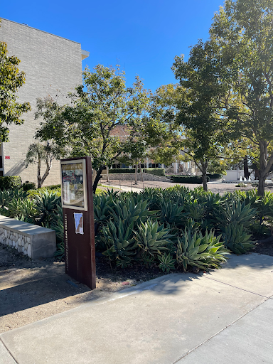 Trees and a visitor map in front of some buildings on a college campus.