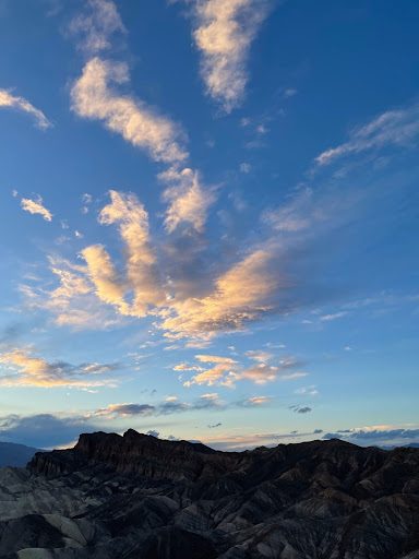 clouds above a mountain range with bands of different rock colors running across it