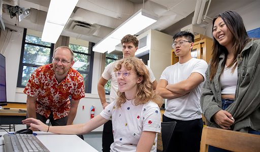 Four students and a professor looking as computational results in a bio lab