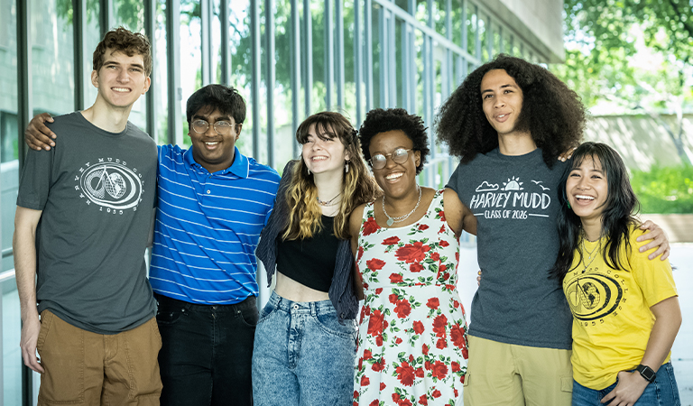 Six students embrace and smile for a photo.