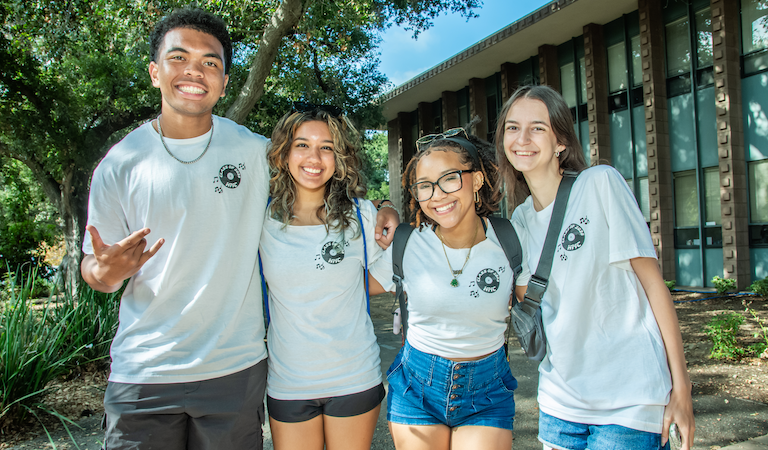 Four students posing in front of building