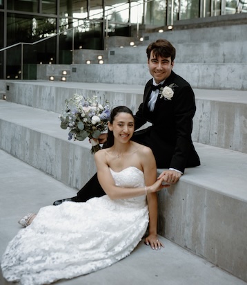 Veronica Rivera and Alex Ozdemir in wedding outfits posing on steps