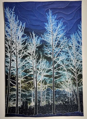 Quilt with silver looking trees on blue background