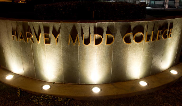 Stone sign lit up saying Harvey Mudd College