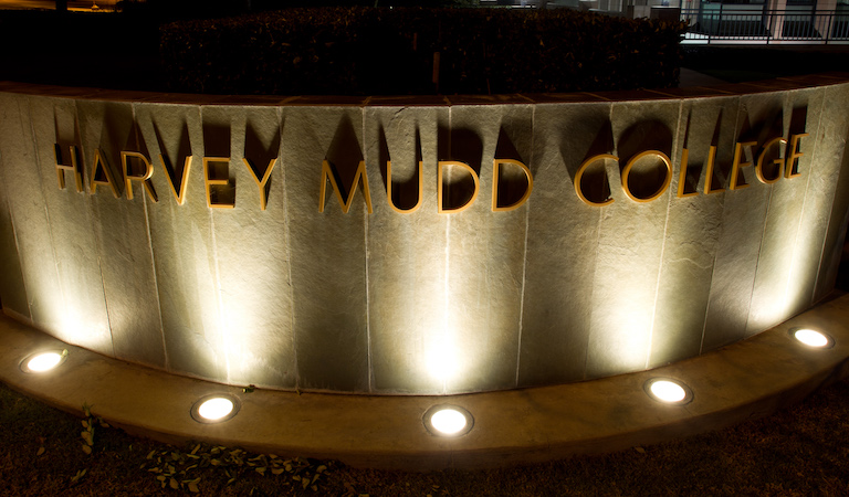 Stone sign lit up saying Harvey Mudd College