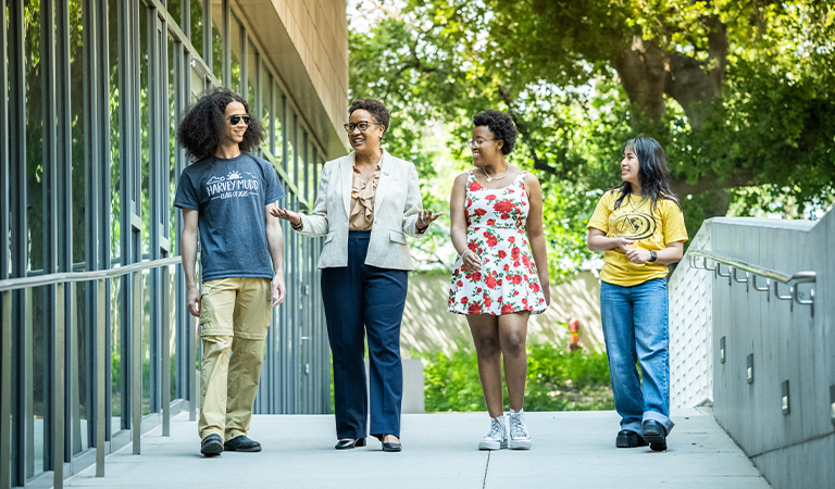 President Harriet Nembhard and students walk down a walkway.