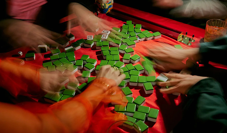 Six hands shuffling mahjong tiles