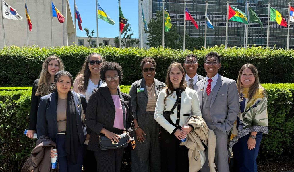 President Nembhard and students in front of international flags and office building