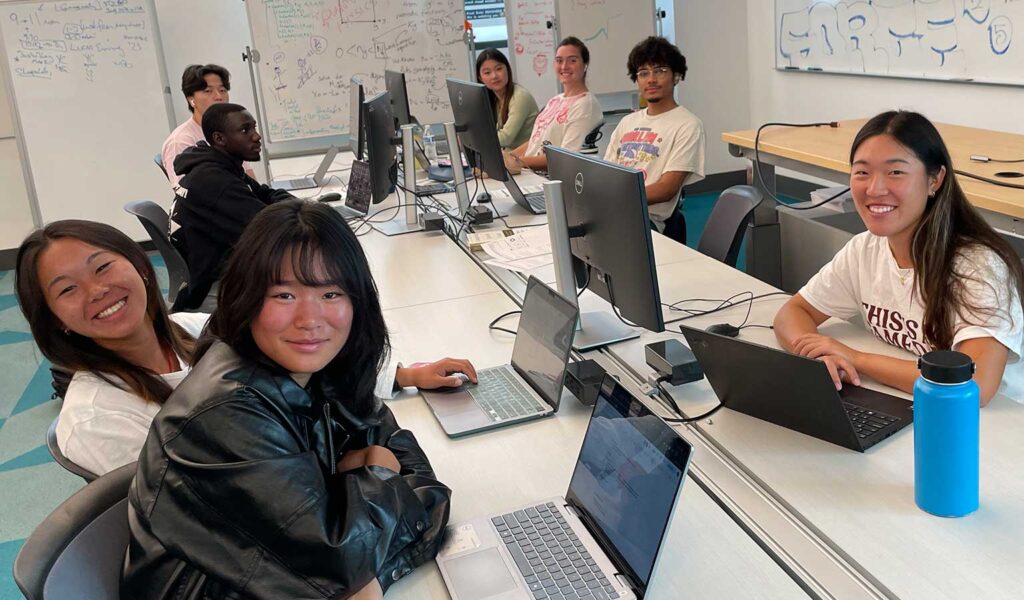 Group of students working at desks with laptops