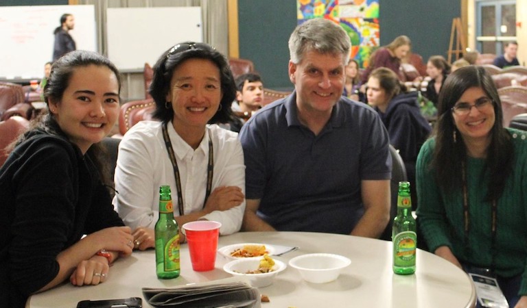Four people at table with drinks and snacks