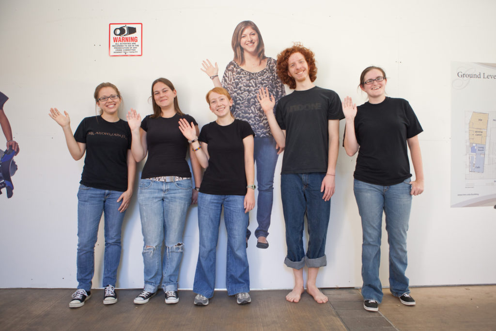 Prof. Hawkins research group in front of her life-size poster