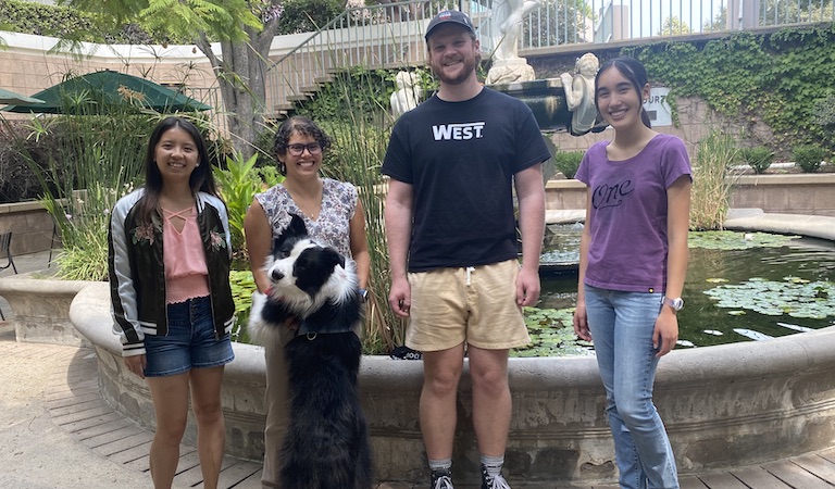 Prof. Hernandez-Castillo and lab students and dog standing in Hixon Court by fountain.
