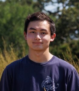 Student head and shoulders in outdoor setting wearing purple t-shirt