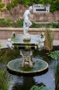 Venus sculpture standing on pedestal in the middle of a fish pond.