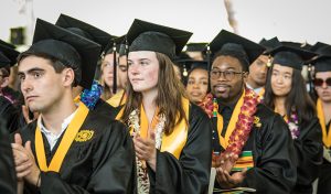 Seated and applauding graduates in academic robes.