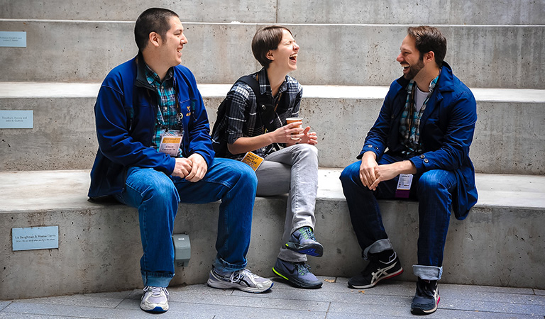 Alumni sitting and laughing in an amphitheater.