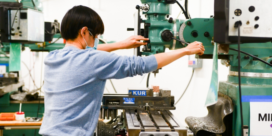 A student operates a mill in the machine shop.