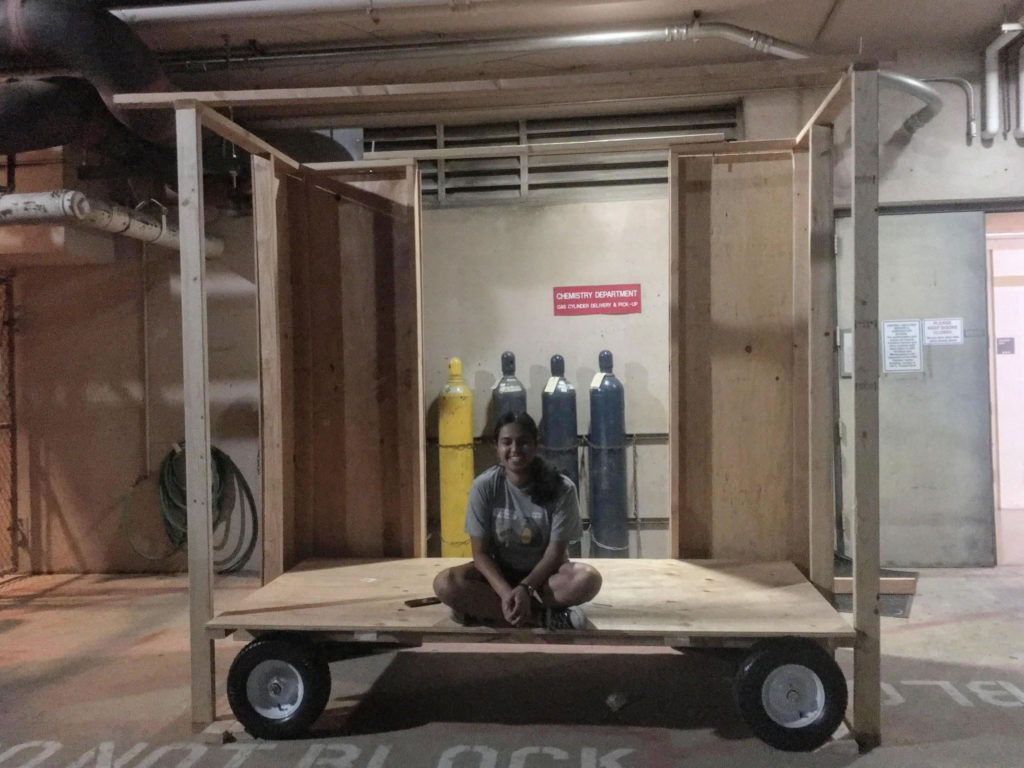 Student sits cross-legged on cart base.