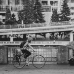 Black and white photo of a woman bicycling on a city street