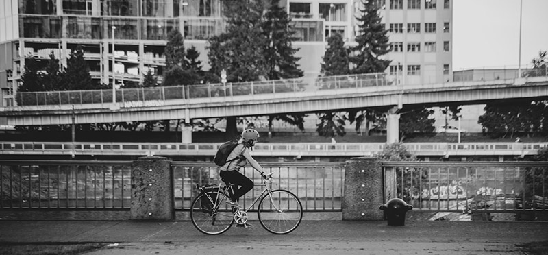 Black and white photo of a woman bicycling on a city street