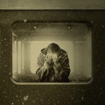 Woman holding head in hands on train