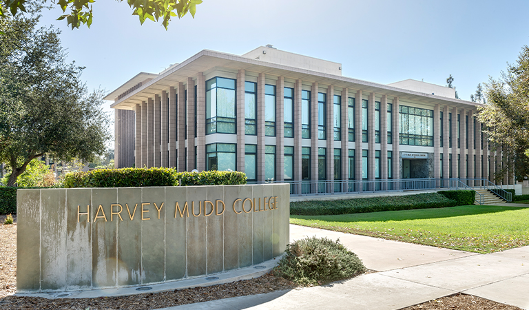 Cement slab with letters spelling "Harvey Mudd College" and the Olin building in the background.