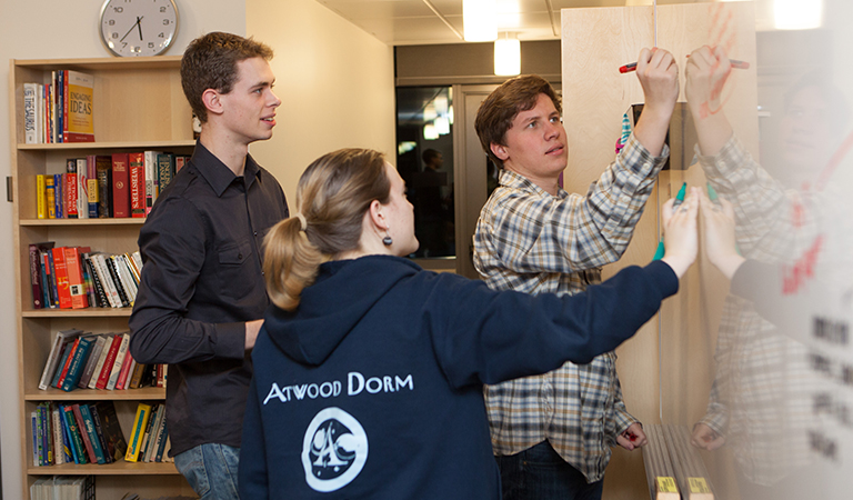 Students writing on a white board.