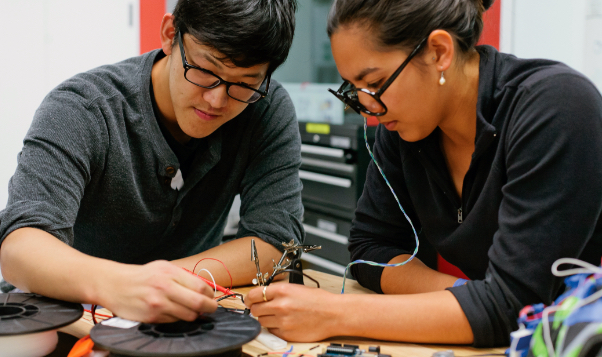 Two students soldering electronics