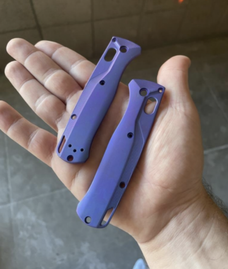 A hand holding two purple tool handles that are made of anodized titanium.