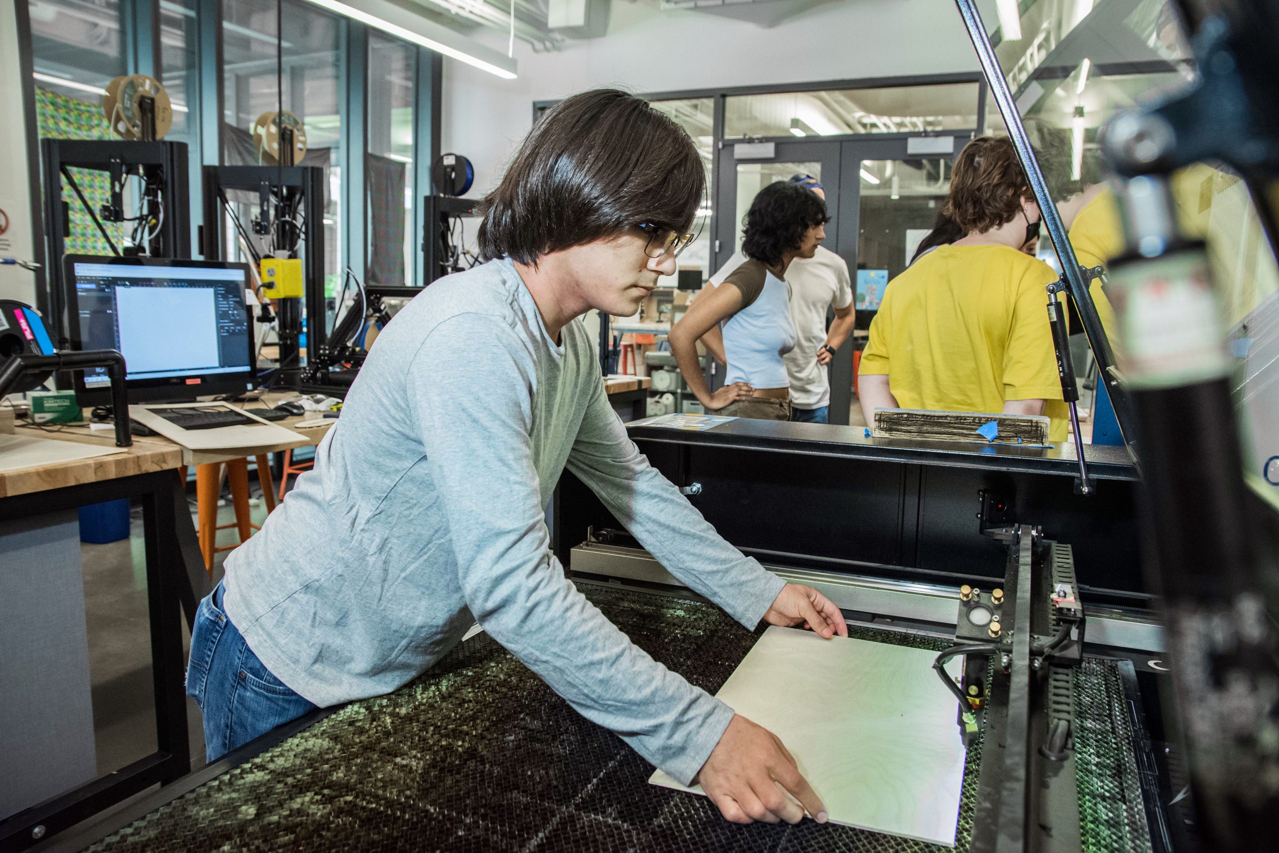 A steward putting wood on the laser cutting bed