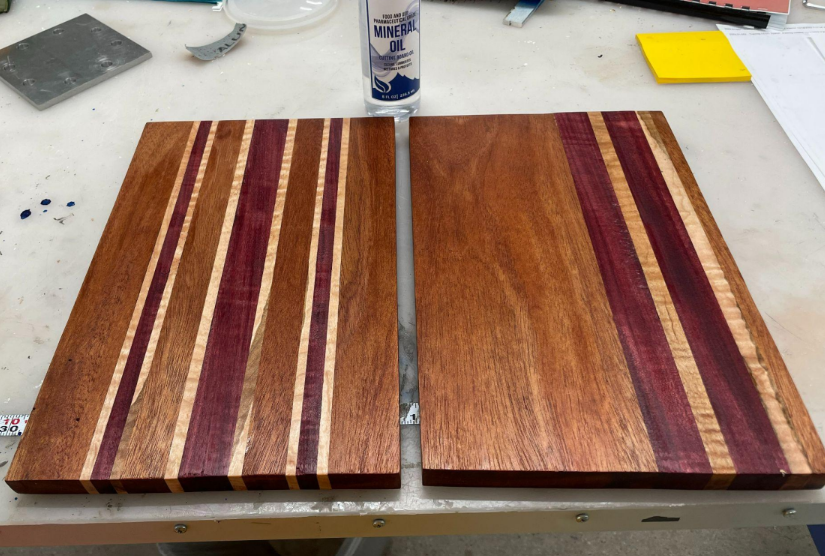 Two rectangular cutting boards with vertical stripes made of different kinds of wood.