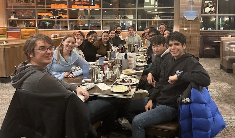 Students with professors at table in restraunt