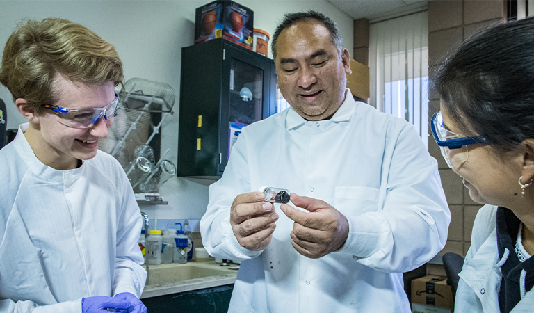 Students and a professor examining an object.