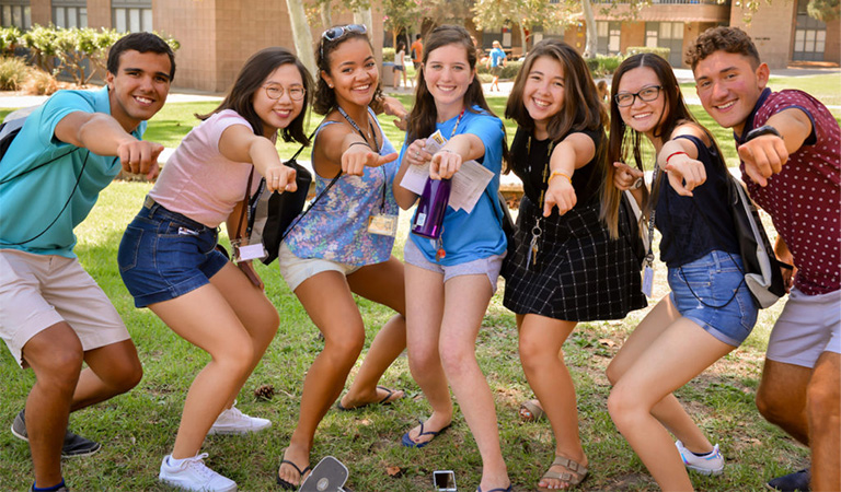 Six students pointing at the camera on orientation day.