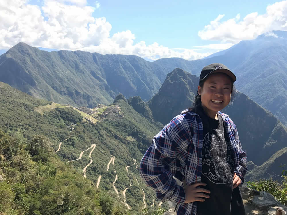 Student with tree-covered mountains in background.